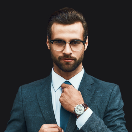 About: A man with glasses and a beard adjusts his tie while wearing a blue suit, white shirt, and wristwatch, standing against a solid black background.